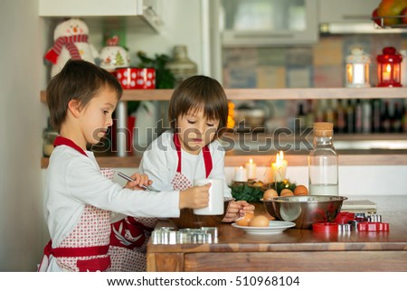 Two sweet children, boy brothers, preparing gingerbread cookies for Christmas, baking at home