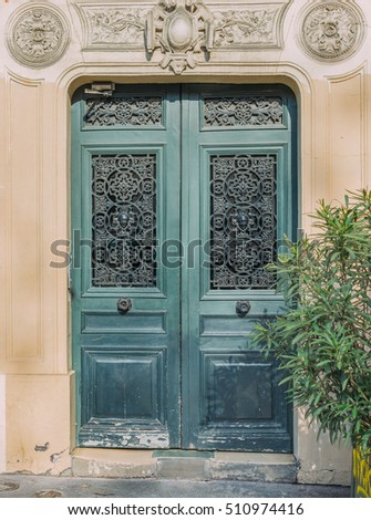 Dark faded green wooden door entrance. Classic european decorated facade. Worn vintage wall with entrance. Postcard concept. Travel inspiration. Luxury estate background. 