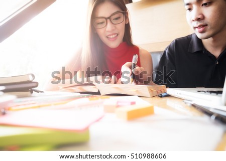 Young woman and man studying for a test/an exam. Tutor books with friends. Young students campus helps friend catching up and learning. People learning education and school concept.