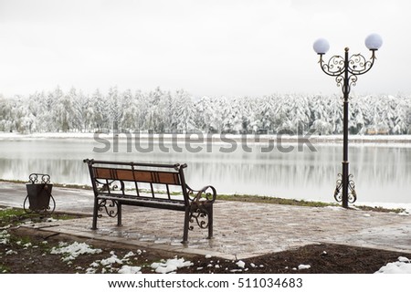 wrought urn bench and lantern on a background of a winter park and lake