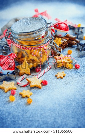 Glass jar with ginger Christmas cookies in the form of stars, blue background,cinnamon sticks, colorful candy.