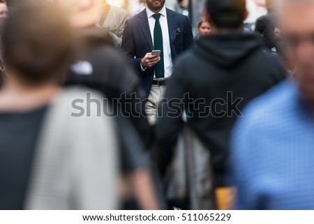 Business people walking from the job in busy city street. Elegant businessman in the people crowd walking and texting on the phone. Royalty-Free Stock Photo #511065229