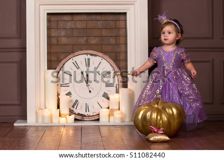 Little princess standing near a magic pumpkin and holding a magic wand in the hands of. Fairy tale. Soft focus.