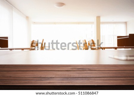 Empty wooden desk space over blurred office or meeting room background. Product display.