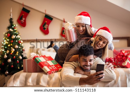 Cheerful friends taking a Christmas selfie with smartphone.