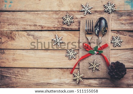 christmas table place setting and silverware, snowflakes, pine cones on wooden background with space.