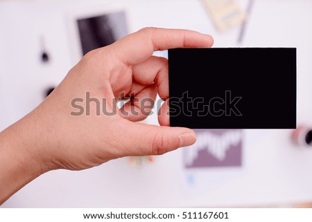 Hand is holding a black business card or black label On the desk in office.
