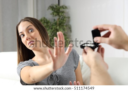 Scared girlfriend rejecting a marriage proposal at home. Humorous situation Royalty-Free Stock Photo #511174549