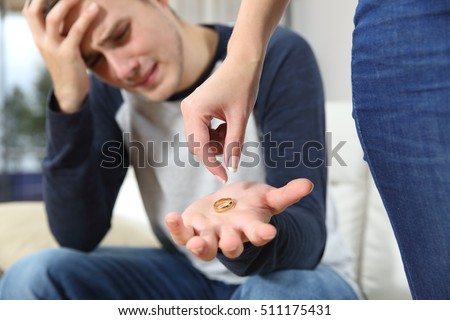 Closeup of a wife breaking up relationship leaving the wedding ring on the hand of her husband in a house interior Royalty-Free Stock Photo #511175431