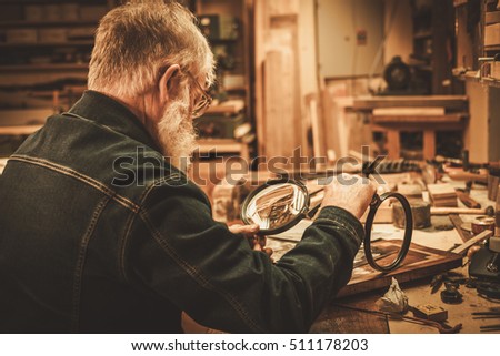 Senior restorer working with antique decor element in his workshop.