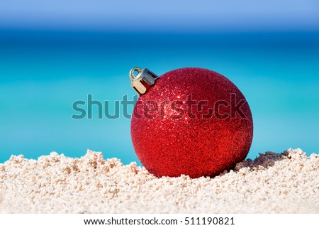 Red fir tree decoration ball on sandy beach, Tropical christmas and New Year celebration 
