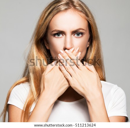 Woman with closed mouth. Female covers her mouth with her hands. Silence, fear, violence. Royalty-Free Stock Photo #511213624