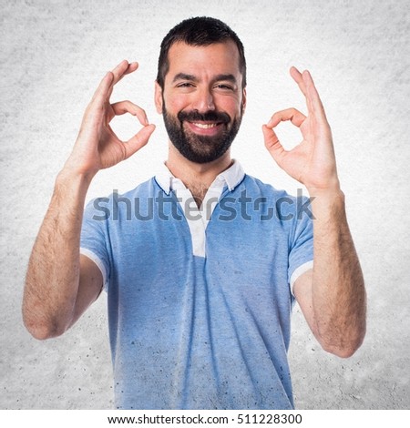 Man with blue shirt making OK sign on textured background