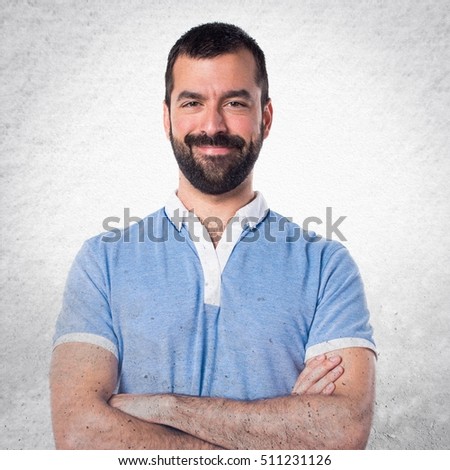 Man with blue shirt with his arms crossed on textured background