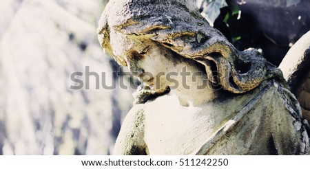Vintage image of a sad angel on a cemetery against the background of leaves (details)