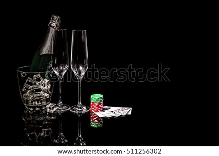 Bottle of champagne in an ice bucket with two wineglasses and playing cards and colorful chips