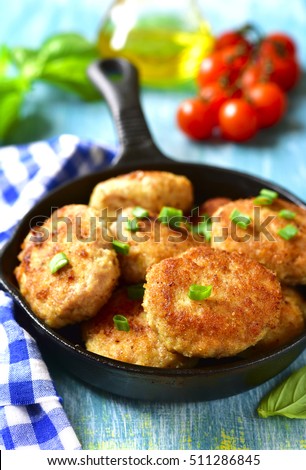 Chicken cutlets in a skillet on a blue wooden background.