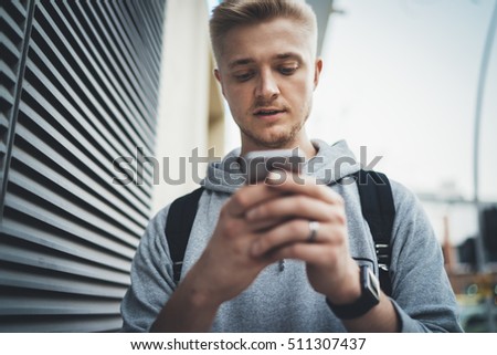 Young hipster guy talking via his smartphone outdoor, male student walking in the city and using an app to play game in the park, conversation or social networking concept