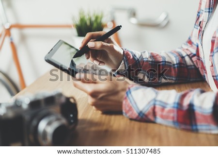 Close-up of female hands using modern graphic digital tablet at home interior, hipster female artist drawing with stylus on touch screen of portable tablet, working at modern loft