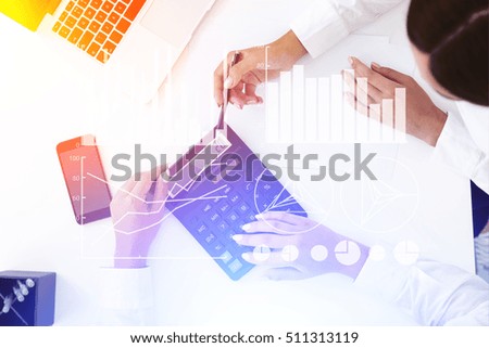 Top view of two pairs of women's hands working with calculator. Graphs are seen in the foreground. Concept of accountant's work. Toned image. Double exposure