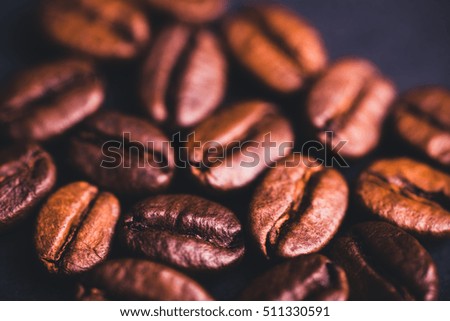 Brown roasted coffee beans, seed on black, blue background. Espresso dark, aroma, black caffeine drink. Closeup isolated energy mocha, cappuccino ingredient.