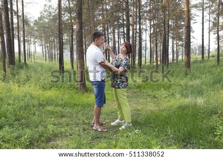 Family, an elderly woman and her son in a park on the weekend activities. An elderly woman and her son dancing in a summer forest. The concept of retirement age and filial love.