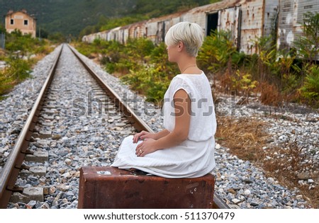 Lonely woman with a suitcase traveling by rail autumn day.