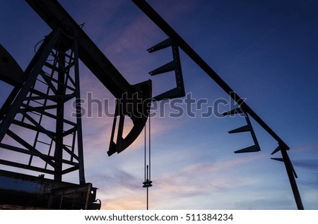 Oil pump and pipeline silhouette during sunset at the oilfield. Oil and gas concept.