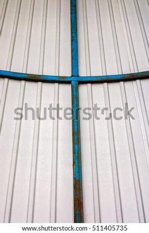 white plastic ceiling with vertical stripes and three-dimensional metal blue vintage cross in the middle, illuminated plastic ceiling in the tunnel, symbolic cross on the ceiling