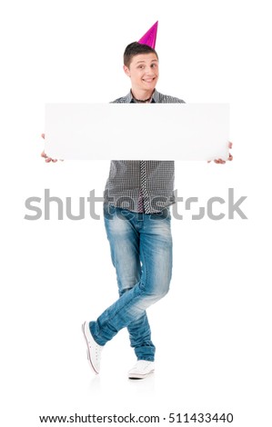 Smiling teen boy in birthday cap holding white board. Young man showing empty billboard sign, isolated on a white background. Advertisement and business concept - caucasian guy with card board.