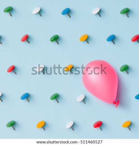 Pink baloon with colorful pins on blue background. Adversity or unique concept. Flat lay. Top view.
