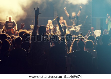 Rock concert, cheering crowd in front of bright colorful stage lights Royalty-Free Stock Photo #511469674