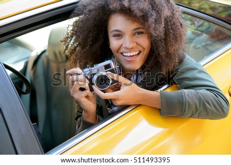 Cheerful girl taking pictures from a yellow cab, New York City                               