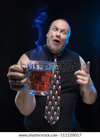Comic actor funny man with a glass of hot drink on a black background, Christmas and New Year