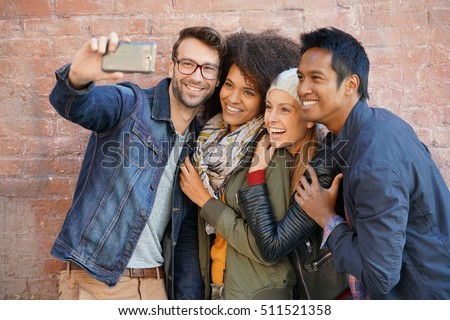 Group of trendy people taking selfie picture, brick wall background                             