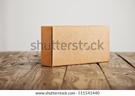 Craft unlabeled cardboard package box presented on stressed brushed wooden table, isolated on white background Royalty-Free Stock Photo #511541440