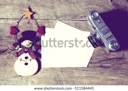 Christmas Decoration with Snowman and Old Photo Camera with Empty Space on Rustic Wooden Background. Image is Retro Filtered.