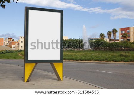 Blank billboard in a green street, with a fountain in the background