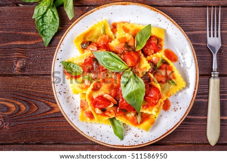 Ravioli with tomato sauce and basil on dark background, top view. Royalty-Free Stock Photo #511586950
