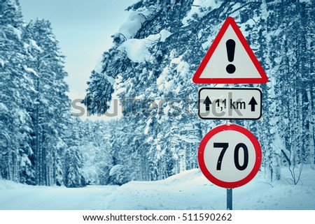 winter view on the road through coniferous forest. Road caution sign in forest landscape