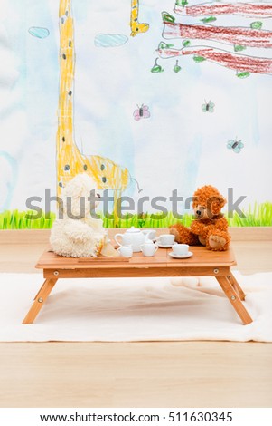 Child's tea set and stuffed toys arranged on small table in child room