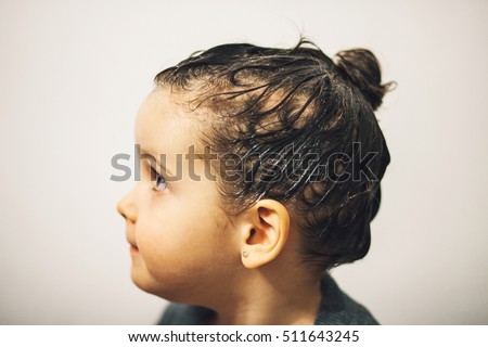 Profile of young girl being shampooed with medicine to treat lice infestation. 