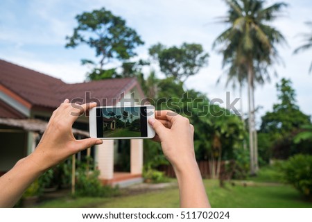 Photographing the house on the phone. Hands with the phone close-up picture. Beautiful house for renting or blog.
