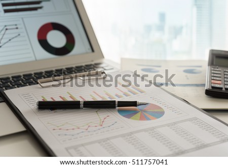 Pen on business graphs report, computer on desk of financial advisor. Accounting background abstract concept. Royalty-Free Stock Photo #511757041
