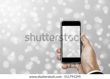 Hand using Smartphone taking a Photo of Defocus Snow Bokeh Lights Background