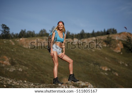 Tourist woman mountain hiker with backpack stands on mountains