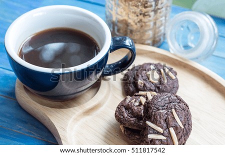 Plate with chocolate cookies and cup of hot coffee on old wooden table. Top view