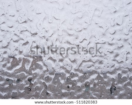 Texture of ice and drops on window glass in inclement winter weather. Close up. Icy rain background