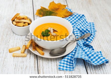 Pumpkin soup with fresh pumpkins on a old wooden table