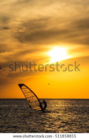 Silhouette of a wind-surfer on waves of a gulf on a sunset